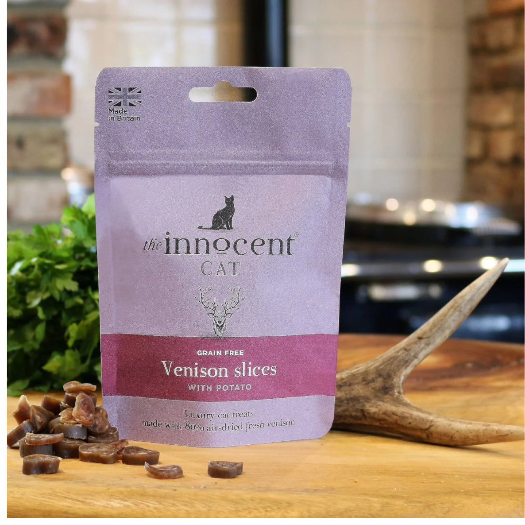 The innocent cat venison slice with potato treats displayed loose beside their packaging and a deer antler.