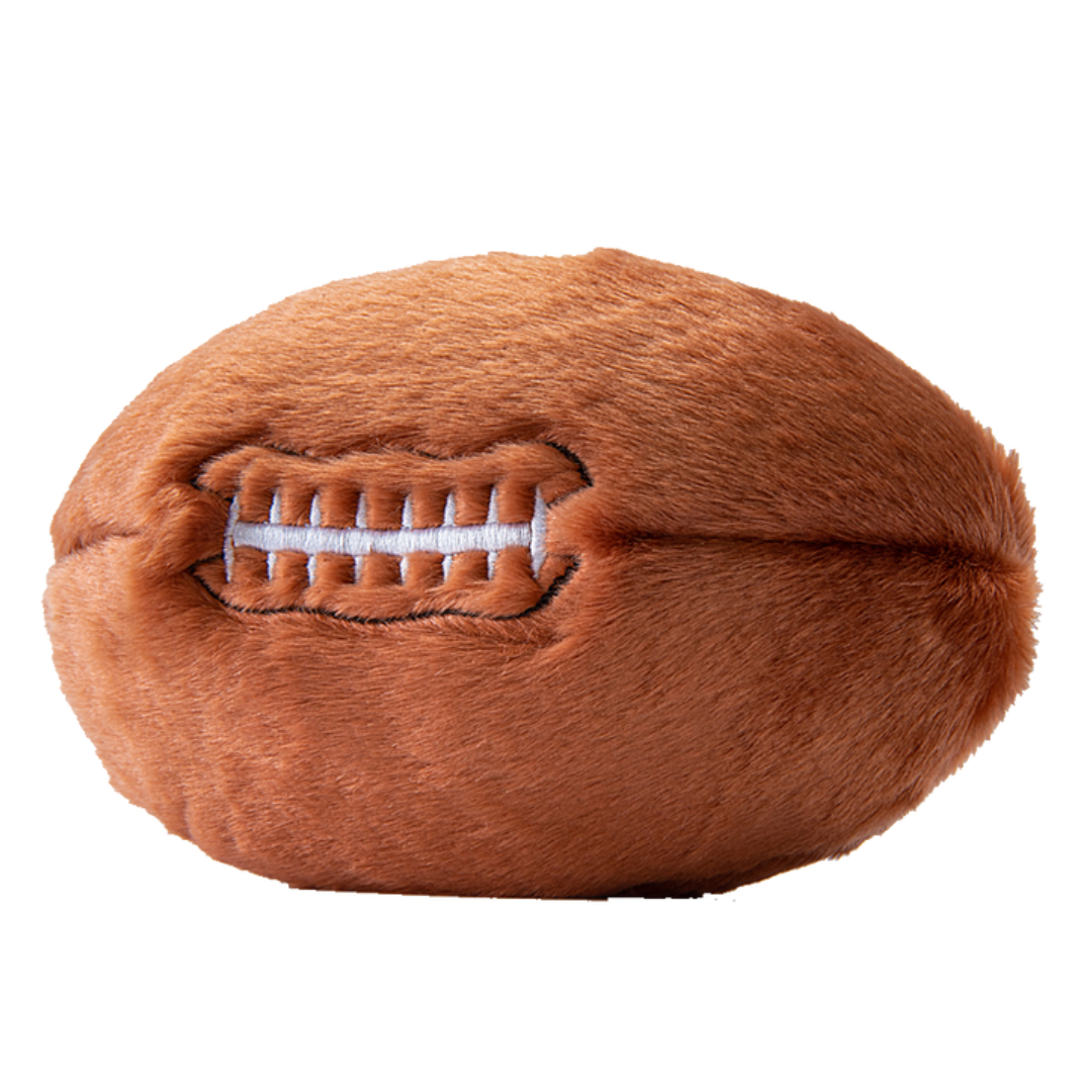 The Fluff & Tuff Football Plush Dog Toy against a white background. It is brown in colour and white stitching to mimic that of a football.