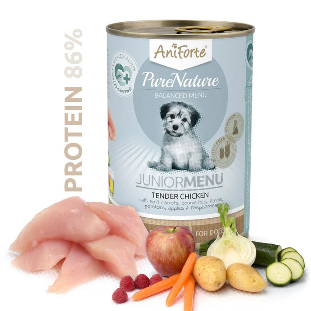 Tin of AniForte PureNature Junior Menu Tender Chicken Wet Puppy food behind the raw ingredients including chicken, carrot and apple.