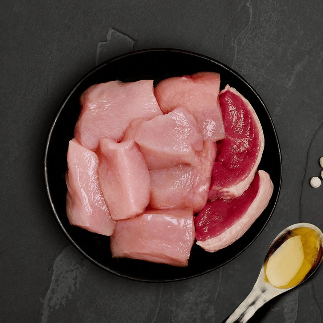 The fresh ingredients of the Canagan Chicken with Duck Cat Food Tin 75g displayed on a plate.