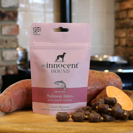 Bag of The Innocent Hound Salmon Bites in front of sweet potatoes and behind a string of treats.