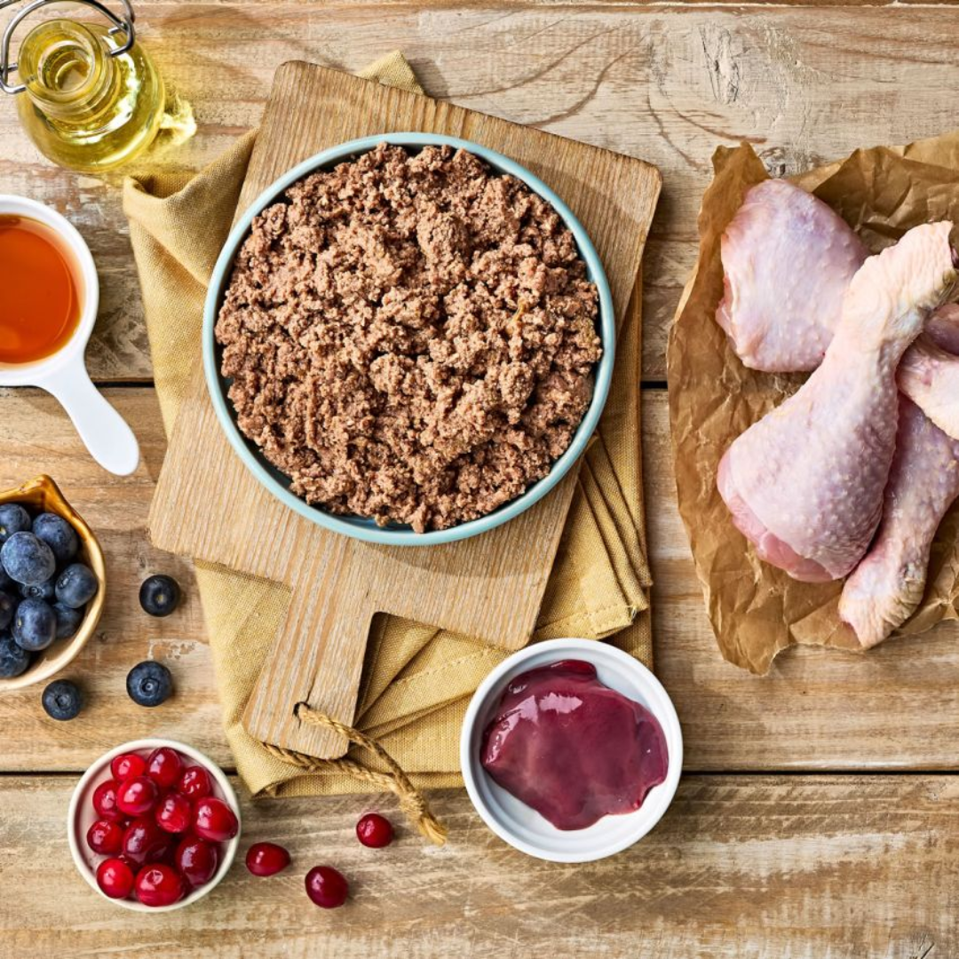 Naturo Indoor Sterilised wet cat in a ceramic bowl, surrounded by raw ingredients.