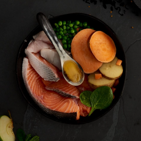Raw ingredients of Canagan Grain Free Scottish Salmon Dog Food in a black dish.