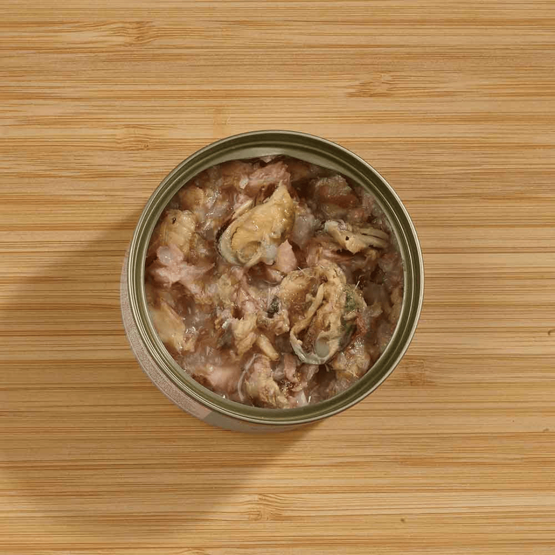 The Fish 4 Cats Sardine and Mussel cat food tin. The lid is off and we can see the soft consistency and chunks of mussel inside. Shot with an ariel view.