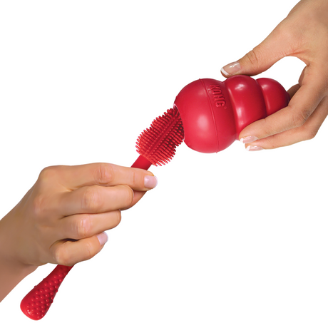 Two hands cleaning a Kong Classic Dog Toy with the Kong Cleaning Brush