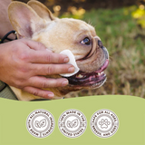 Hand wiping the face of a French Bulldog with a Natural Dog Company Wrinkle Wipe. Icons below the photo say "Made with all natural ingredients. 100% made in the USA, and Safe for all ages, breeds and sizes"