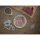 Raw Tuna, squid rings, and rice on a wooden surface with a small bowl of broth. There is a bowl of Fish 4 Cats Tuna with Squid in the middle 