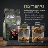 Kudo Lamb & Rice dog food package with two glasses of water comparing cold-pressed and standard extruded kibble and how they digest.