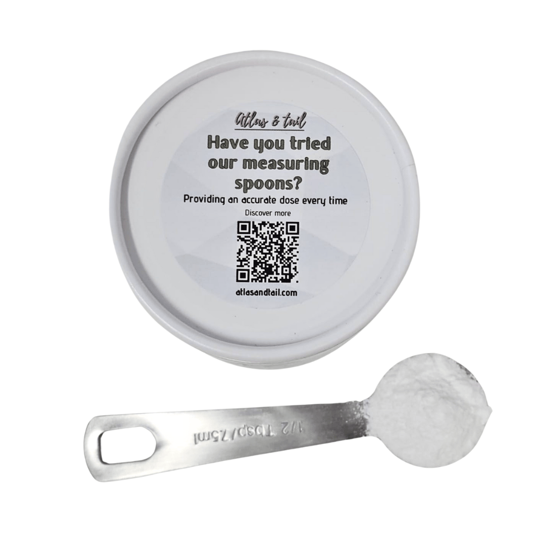silver measuring spoon with measurements etched on, and a container with a sticker laying on a white background