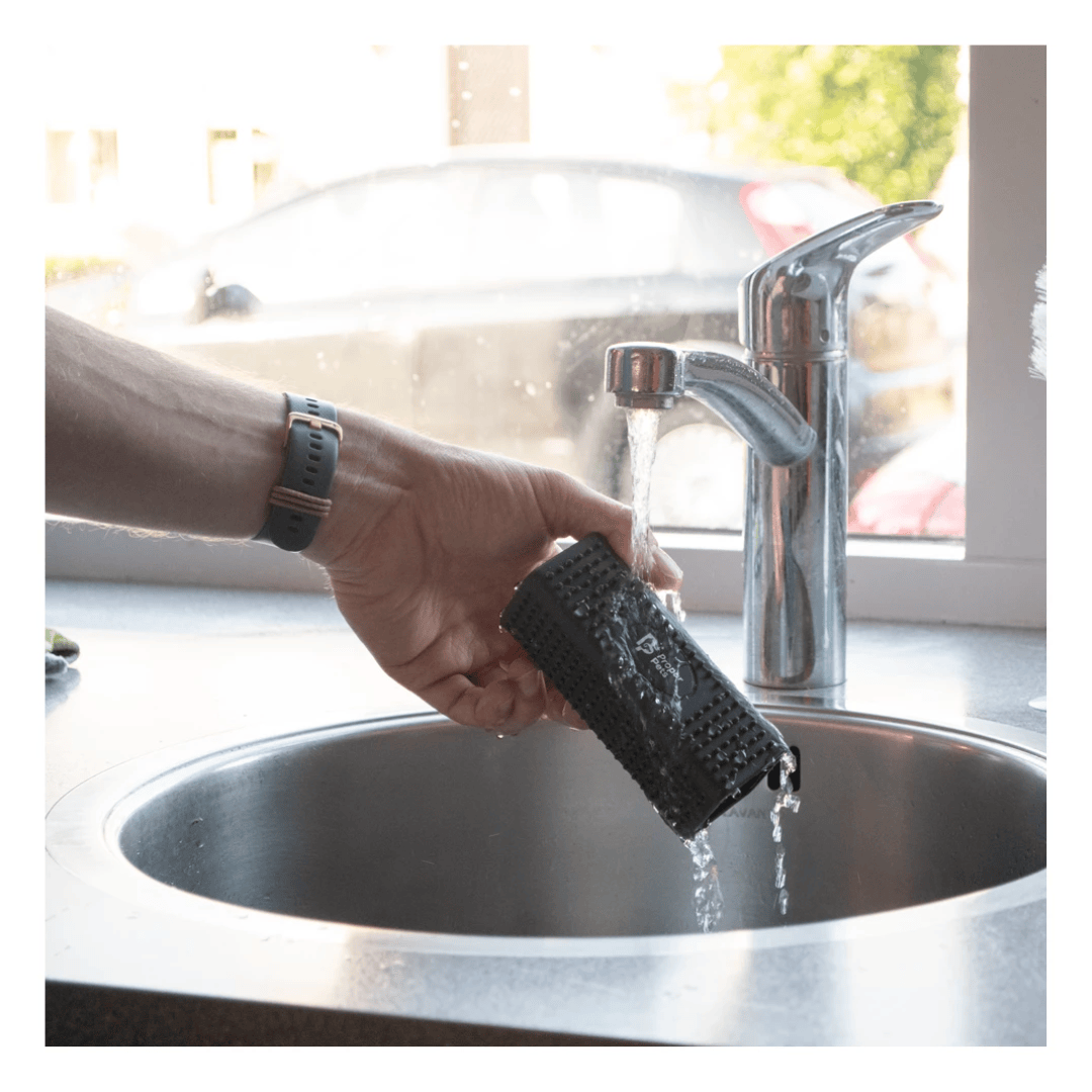 A person is washing their proper pets hair remover brush under running water from the tap