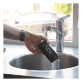 A person is washing their proper pets hair remover brush under running water from the tap