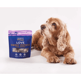 Dog sitting next to a package of Fish4Dogs Love Sweet Potato Fish Wraps on a white background
