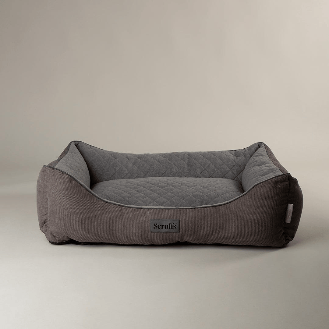 Grey pet bed with quilted design on a beige background