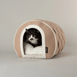Cat peeking out from a beige Stockholm Cat Cave pet bed with a white interior on a neutral background