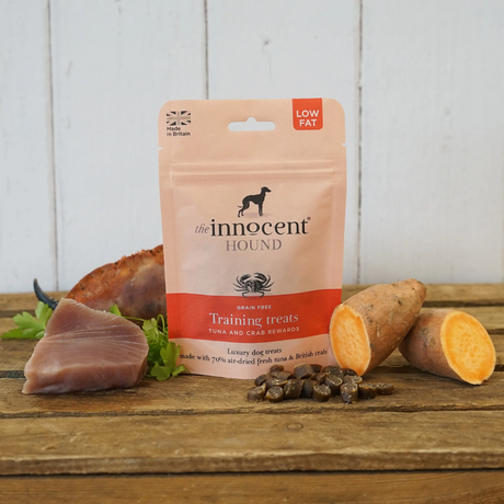 Bag of Innocent Hound Training Treats Tuna and Crab Rewards on a wooden surface, surrounded by raw ingredients and loose treats.